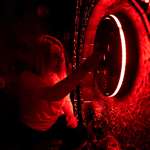 A woman trying to solve a puzzle in a dimly lit room at The Great Escape Game.