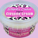 A clear plastic tub labeled “Steph’s Cakes Vegan Clotted Cream” with a pink and leopard-print design. The text highlights “Thick & Creamy” as a feature of the product.