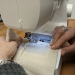 A close-up of someone sewing on a sewing machine.