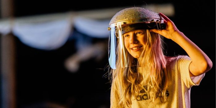 A person, in a dark environment, is smiling. They are wearing protective head gear with a visor.