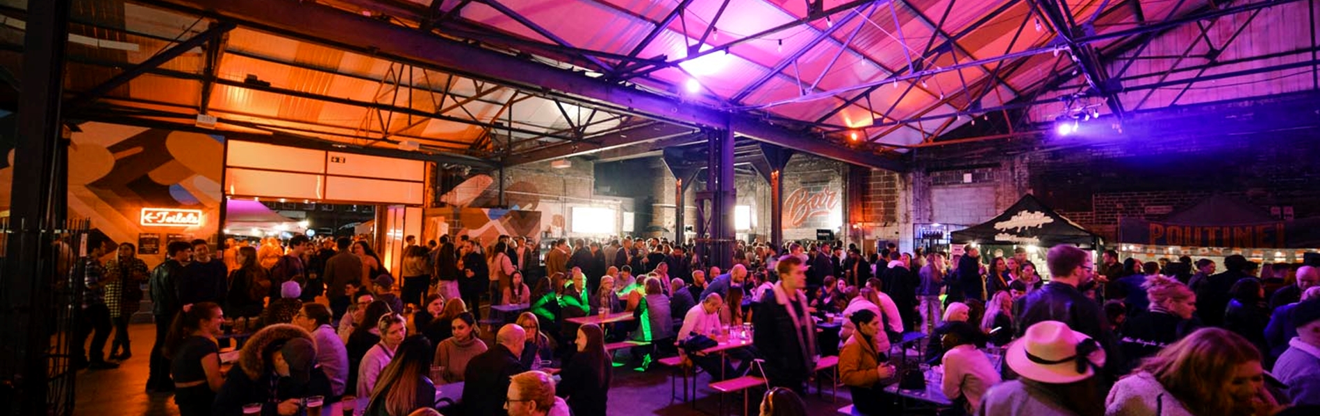 A view inside the Peddler market, there are lots of people seated at tables, eating and chatting.