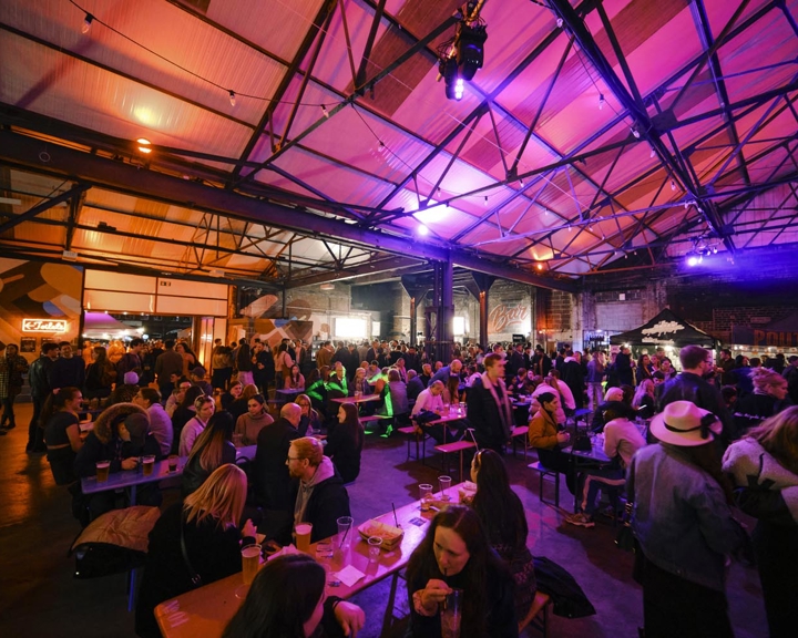 A view inside the Peddler market, there are lots of people seated at tables, eating and chatting.