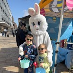 Two children posing for a photo with a person dressed as the Easter Bunny on The Moor.