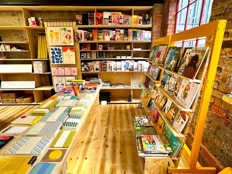 The interior of La Biblioteka bookshop, with all the walls lined with wooden shelves filled with books for sale.