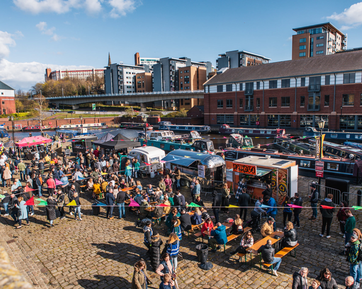 Quayside Market At Victoria Quays in full flow with people wandering about, in bright sunshine, and sitting at trestle tables eating.