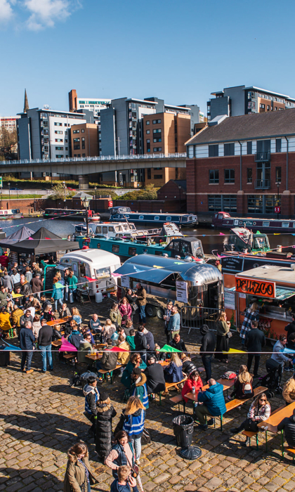 Quayside Market At Victoria Quays in full flow with people wandering about, in bright sunshine, and sitting at trestle tables eating.