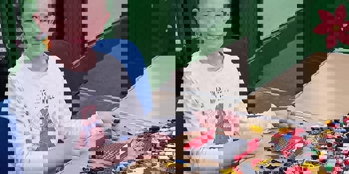 A child sat at a table playing with Lego.