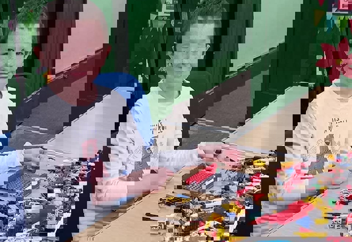 A child sat at a table playing with Lego.