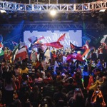A huge performance on stage with people in traditional cultural dress from around the world holding flags from a huge range of countrys.