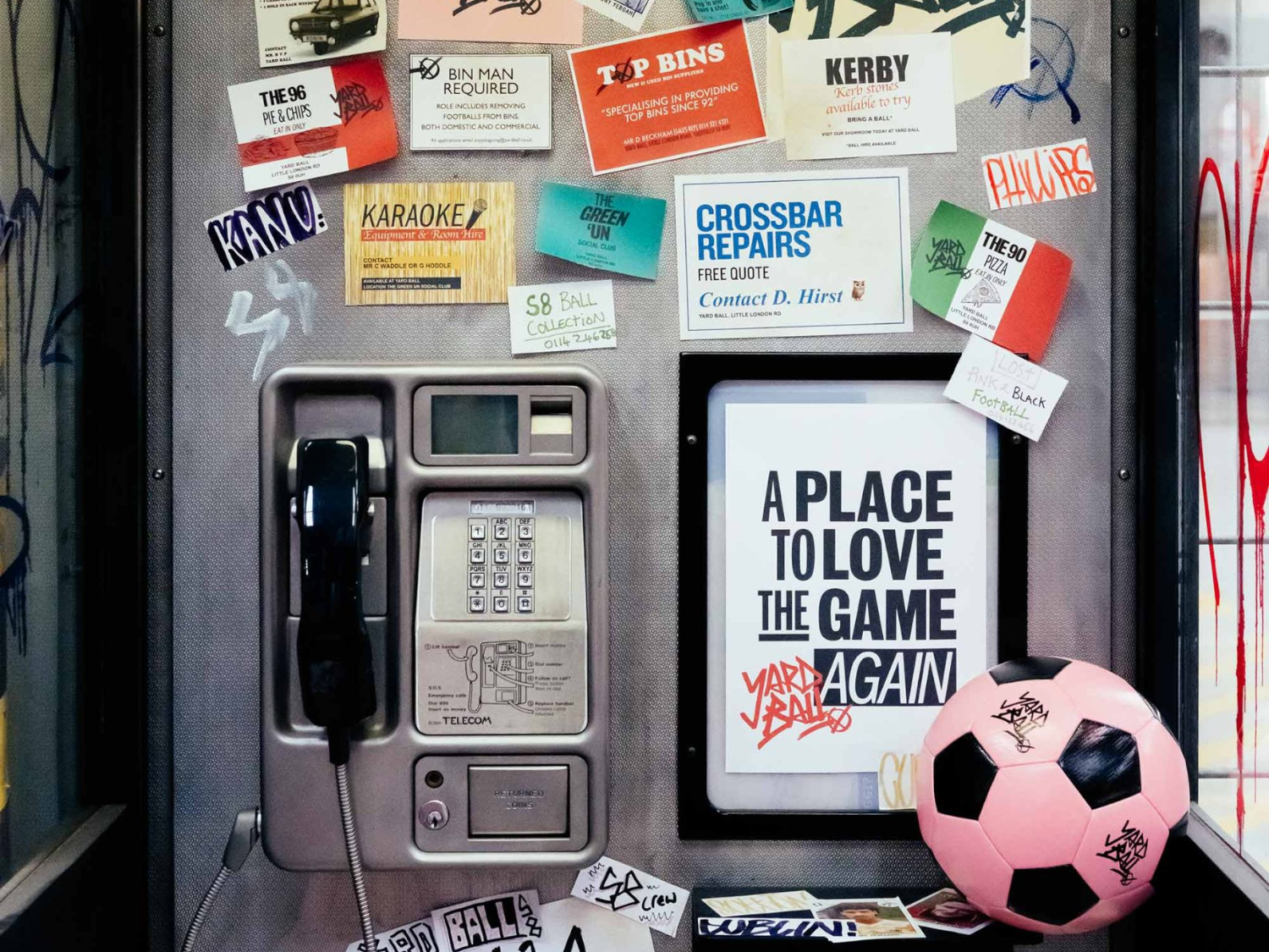 An interior shot of Yard Ball that has been made to look like a public phone booth. There is a pink football on a shelf.