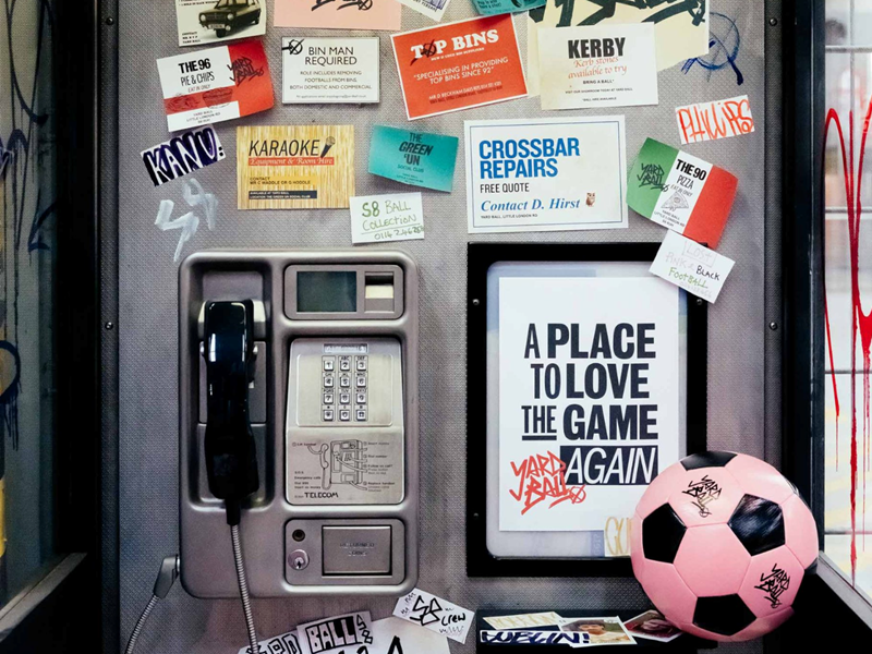 An interior shot of Yard Ball that has been made to look like a public phone booth. There is a pink football on a shelf.