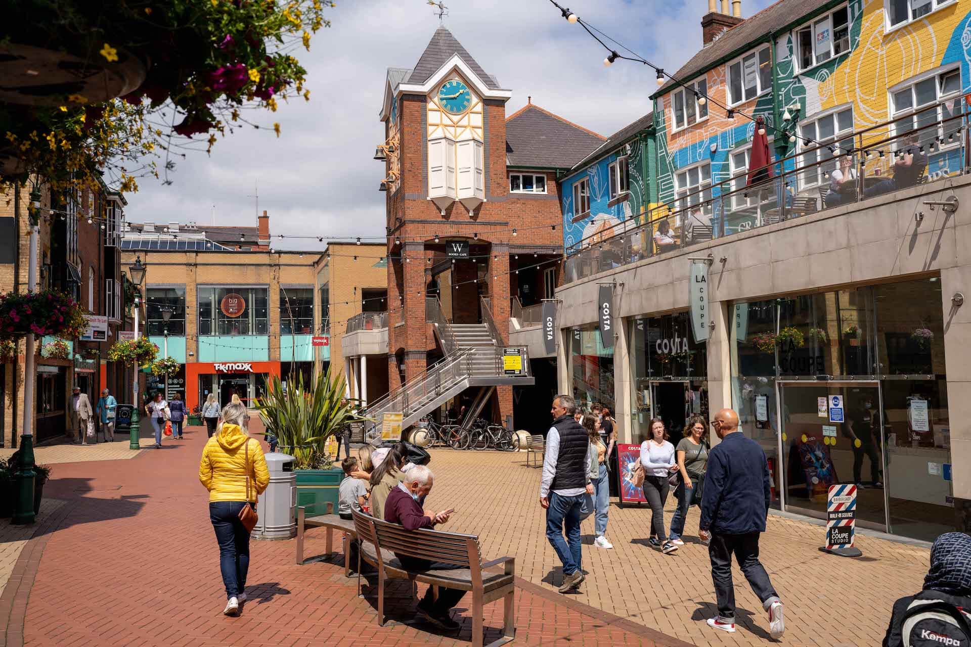 Lots of people are walking about in Orchard Square on a sunny day.