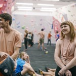 People having fun at an indoors climbing wall.