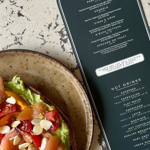 A salad on a table next to La Bottega's menu. 