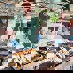 A street food trader turns an array of meat items sizzling on a BBQ