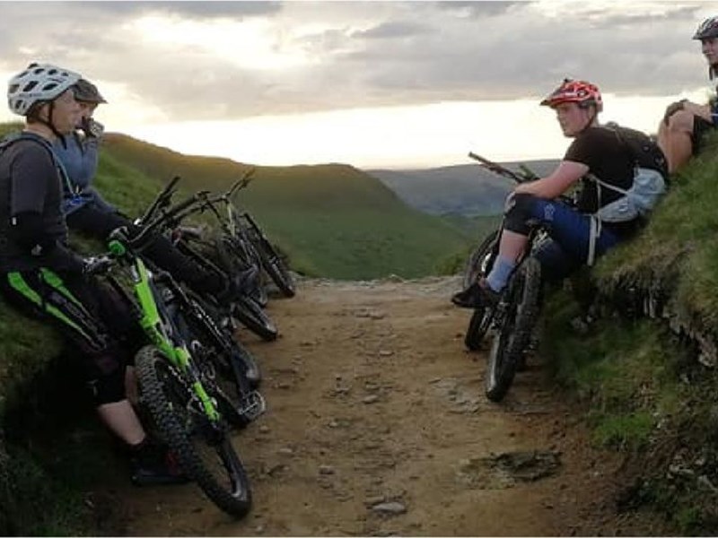 People mountain biking on a dirt track in the countryside.