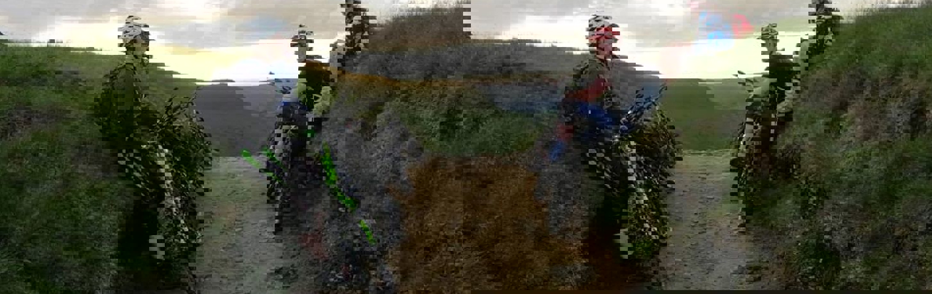 People mountain biking on a dirt track in the countryside.