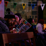 Two men sat down next to eachother reading the events programme for Sheffield Adventure Film Festival
