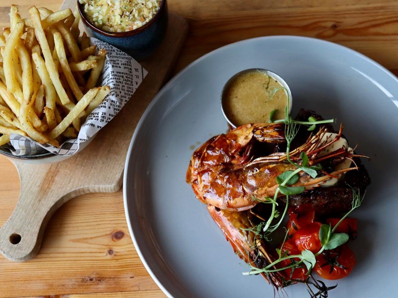 Prawns on a plate with a bowl of french fries at Butcher & Catch.
