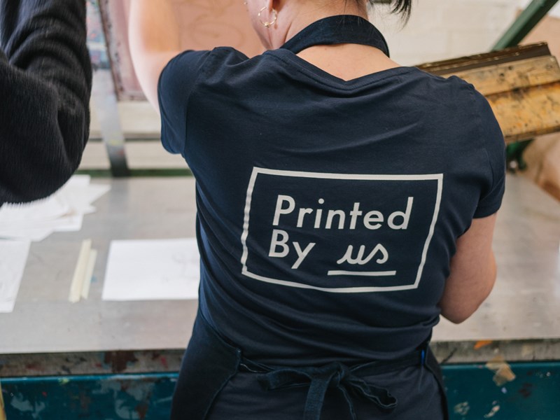 A woman screen printing at Printed by Us.