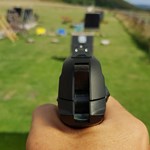 A hand holding a pistol that is aimed at a target on a shooting range.
