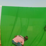 People hanging a green cloth over a goal post.