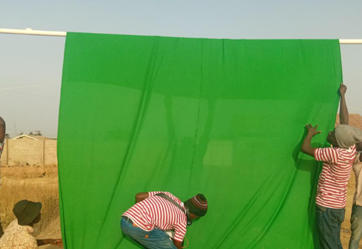 People hanging a green cloth over a goal post.
