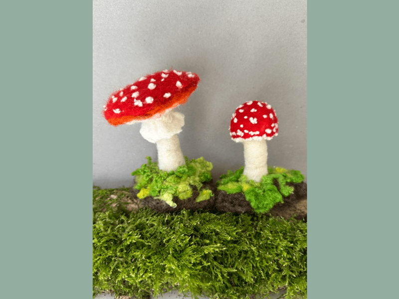 Two felted mushrooms on a log.