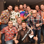 A group of men enjoying a stag do. One of the men wears a sash that says 'Groom to be'.