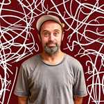 A picture of a man in a hat stood infront of a red background that has squiggly lines