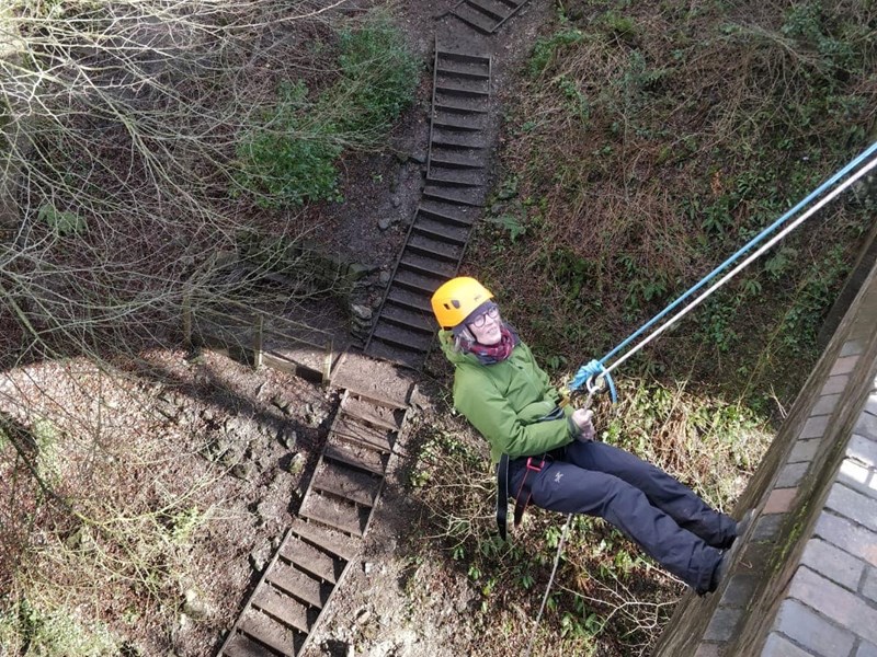 A person abseiling, out in the countryside.