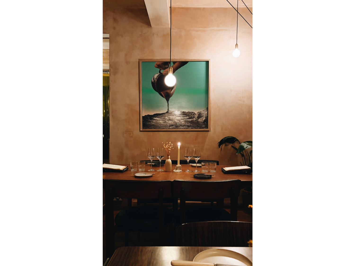 The interior of Restaurant Elm with a table laid out for two, under a large painting.