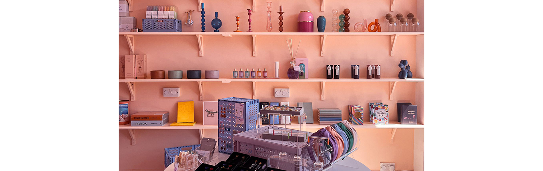 Interior shot of The Stylists Lifestyle Store with a table and shelving displaying various house wares.