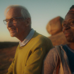 Two people sit smiling, outdoors.