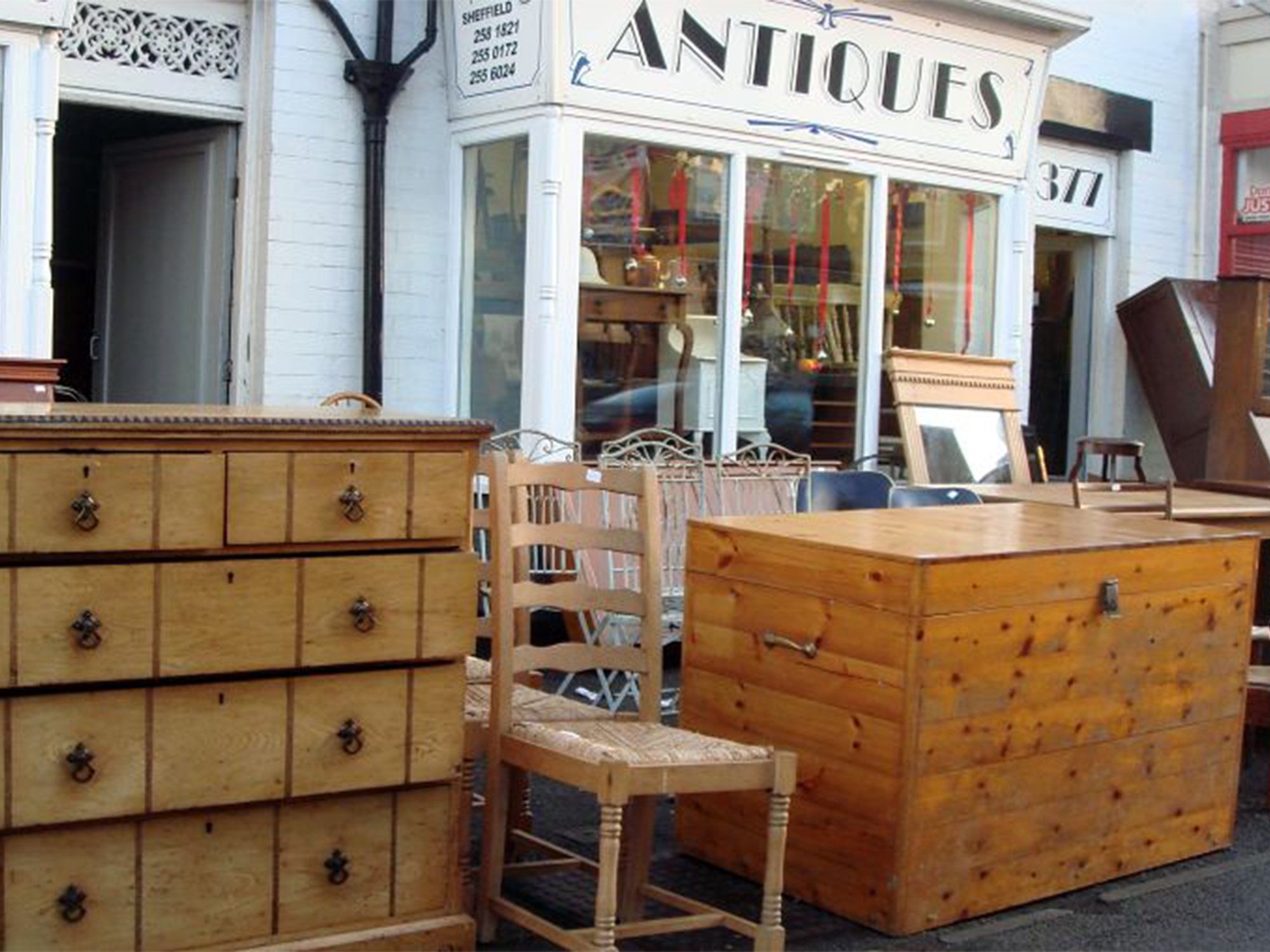 Wooden furniture displayed on the pavement outside Dronfield Antiques Of Sheffield.
