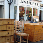 Wooden furniture displayed on the pavement outside Dronfield Antiques Of Sheffield.