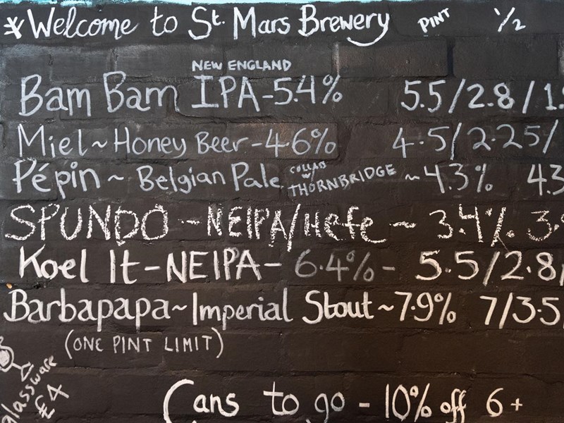 A hand written board with beer names and prices at The Brewery of St Mars of the Desert.