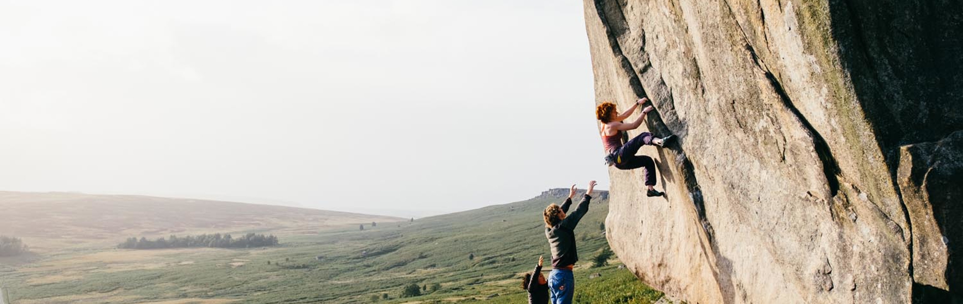 Three people bouldering in the peak district. 