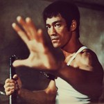 An iconic still from The Way Of The Dragon with Bruce Lee holding nunchucks. 