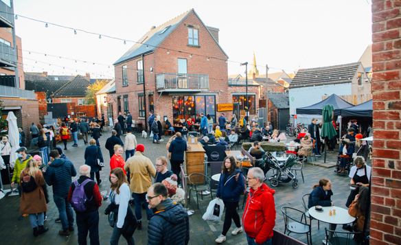 A large crowd of people looking round an outdoor market on Sharrow Vale Road in Sheffield.