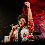 A person singing into a microphone on a stage.