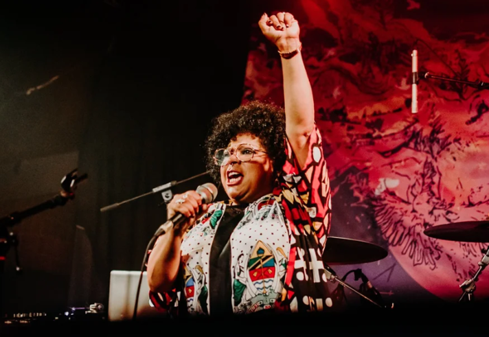A person singing into a microphone on a stage.