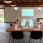 A room set up for a meeting, with a projector screen showing a slide deck, at Manor Oaks House.