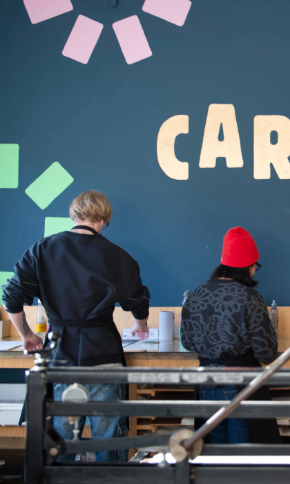 Two people standing, working at a bench in a print studio.