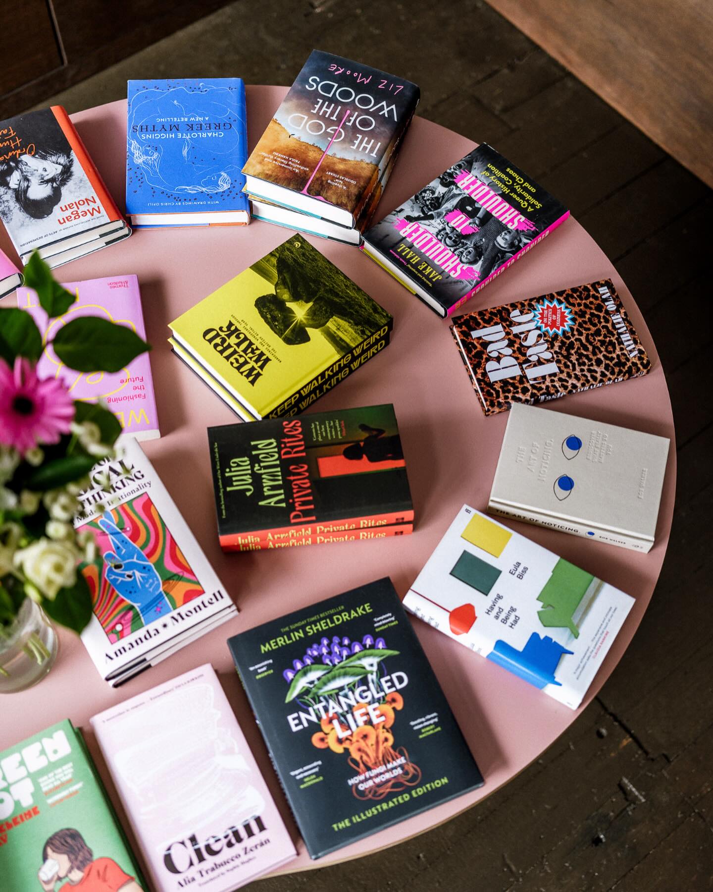 A pink round table with books arranged in a circle around the table.
