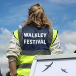 A person in a high viz jacket with the words 'WALKLEY FESTIVAL' on the back.
